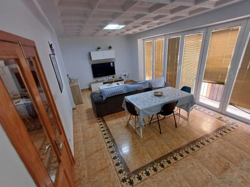 Saló modern d'un apartament a Algemesí amb taula de menjador, sofà, televisor i portes de vidre al balcó