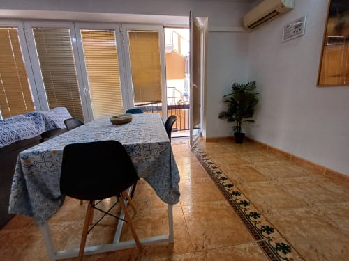 Menjador espaïós en apartament d'Algemesi amb sòl de suro, cadires negres modernes, portes de vidre que s'obren al balcó