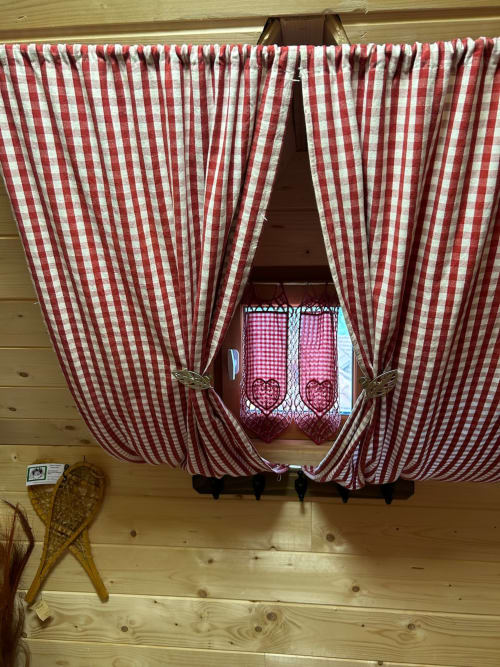 Des rideaux vichy rouge et blanc encadrent une fenêtre de la cabane Chouette aux Cabanes des Marchous, Granges-Aumontzey