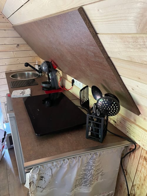 Compact kitchen setup in Cabane Marmotte cottage with espresso machine, black microwave, cooking utensils and storage at Les