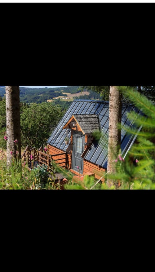 Cozy wooden cottage L'Écureuil nestled in forest at Les Cabanes des Marchous, Granges-Aumontzey, with metal roof and valley