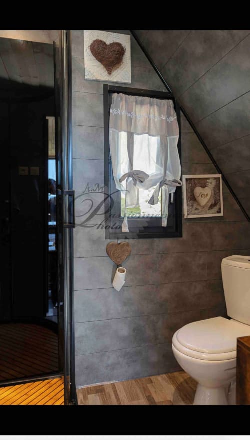 Modern bathroom in cottage at Les Cabanes des Marchous with tiled walls, toilet, shower enclosure, and heart-themed decor