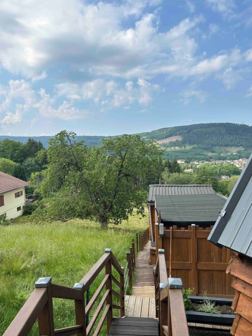 Wooden deck overlooking green hills and village in Granges-Aumontzey, France from Cabane L'Écureuil cottage