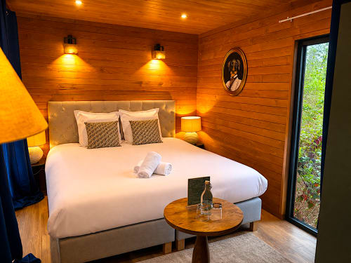 Warmes Holzschlafzimmer in Les Lodges de Vaugrigneuse mit Kingsize-Bett, Gartenblick und Ambientelicht