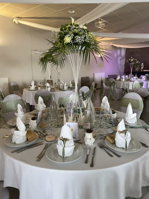 Elegant banquet table setup at Le Domaine De La Marnière in Villainville with white linens, green chair accents, and tall