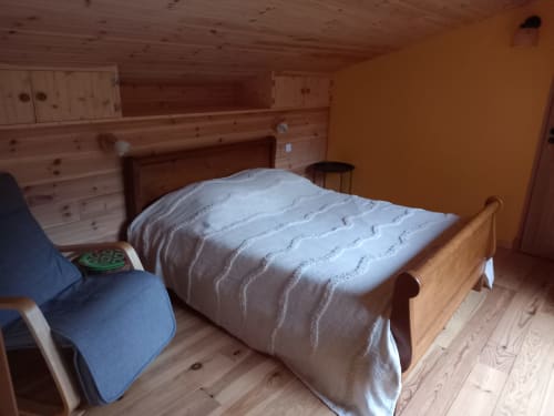 Chambre douillette du gîte Le Petit Nid à l'Eco Gîte du Mandala avec lit en bois et édredon blanc matelassé