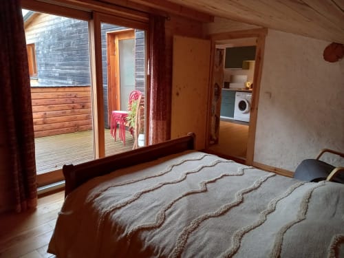 Chambre douillette du gîte Le Petit Nid à l'Eco Gîte du Mandala avec lit en bois, terrasse vue montagne et accès cuisine