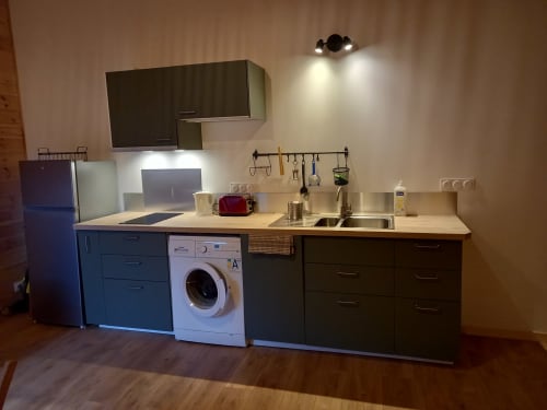 Cuisine moderne avec évier en inox, machine à laver et meubles sombres au gîte Eco Mandala