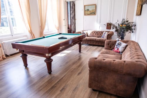 Élégante salle de billard du Château Du Landin avec table de jeu, sièges en cuir marron et baies vitrées lumineuses