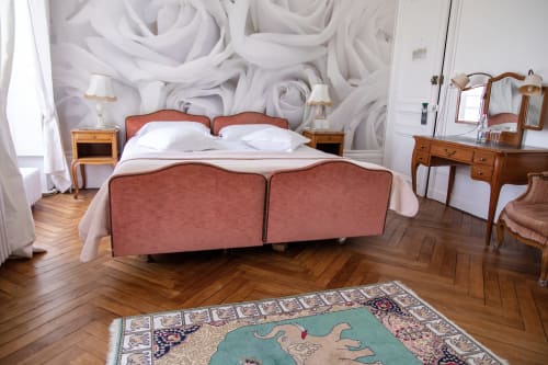 Chambre élégante au Château Du Landin avec lit à tête de lit corail, papier peint aux roses blanches, mobilier en bois et tapis à motifs