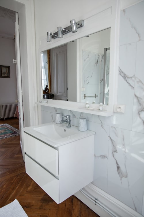 Salle de bain moderne aux accents en marbre, lavabo de meuble-vasque, grand miroir et douche au Château Du Landin