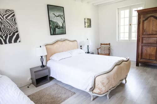 Chambre élégante du Château Du Landin avec lit capitonné, draps blancs, art zébré, armoire en bois et vue sur le jardin