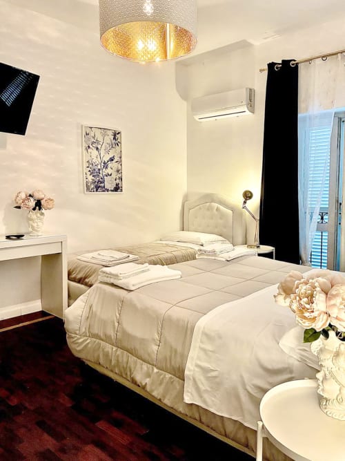 Camera elegante del Bresbot B&B a Bressana con letto color crema, pareti bianche, lampada a sospensione dorata e pavimento bordeaux