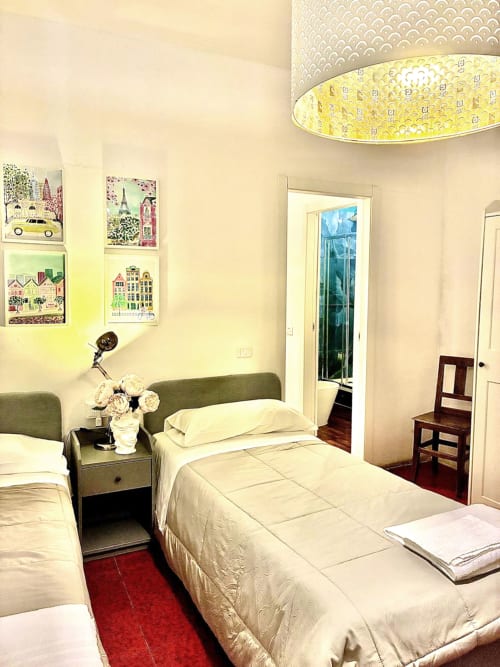 Bright family room at Bresbot B&B in Bressana with twin beds, green headboard, artwork, and garden view access