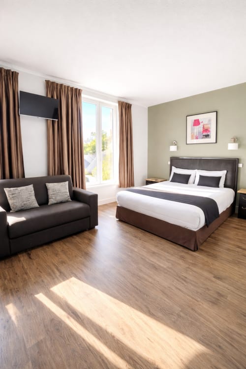 Chambre avec vue sur le jardin à l'Hôtel Des Cèdres, Orléans : lit queen-size, canapé et décoration contemporaine