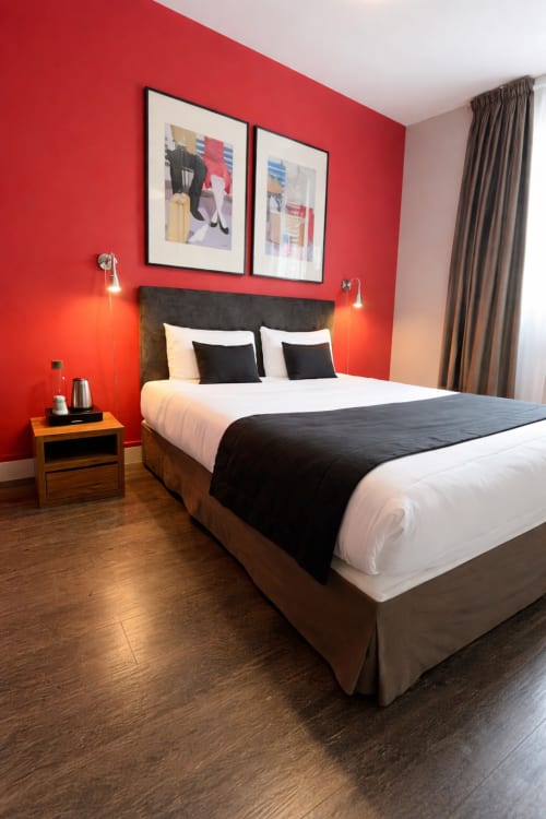 Chambre d'hôtel moderne à l'Hôtel Des Cèdres à Orléans avec murs rouge vif, tête de lit sombre, literie blanche et style contemporain