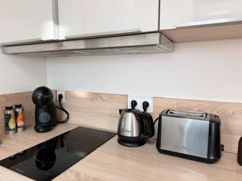 Cuisine moderne de la villa Maison ARLOÉ avec machine à espresso, bouilloire et grille-pain sur plan de travail en bois, La Rochelle.
