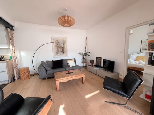 Séjour contemporain de la villa La Maréchale à Maison ARLOÉ, La Rochelle, avec canapé gris, table en bois et vue sur la ville