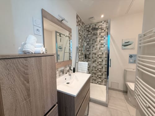 Salle de bain moderne de la villa La Maréchale, Maison ARLOÉ à La Rochelle, avec lavabo, miroir et douche à l'italienne carrelée en mosaïque