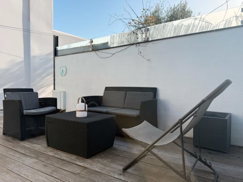 Terrasse moderne sur le toit de la villa Maison ARLOÉ à La Rochelle avec mobilier en rotin noir, table à manger et chaise longue