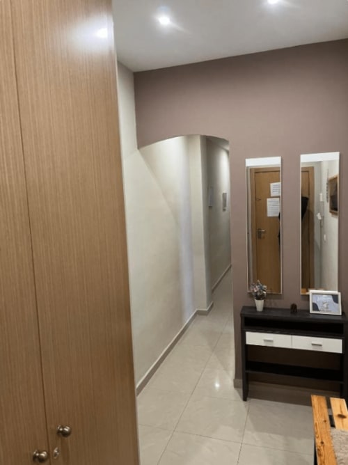 Modern apartment hallway at Algemesi Home with wooden doors, dark dresser, mirrors, and tile flooring