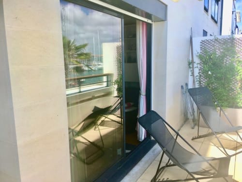 Terrasse ensoleillée de l'appartement Le Chalutier à La Rochelle avec transats, vue sur le port et aperçu de la marina