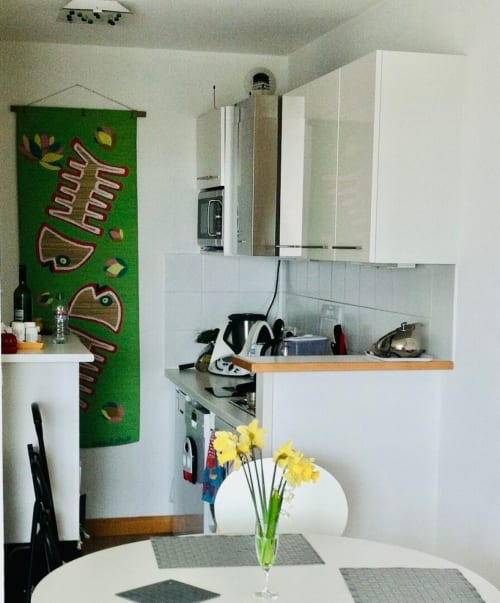 Cuisine moderne avec placards blancs, art mural taco vert, fleurs jaunes et cuisinière. Appartement Maison ARLOÉ à La Rochelle.