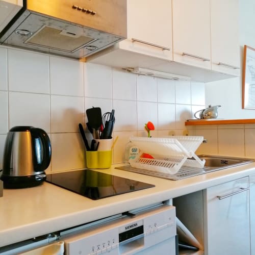 Cuisine moderne de l'appartement Le Chalutier à la Maison ARLOÉ, La Rochelle, avec bouilloire en inox et placards blancs