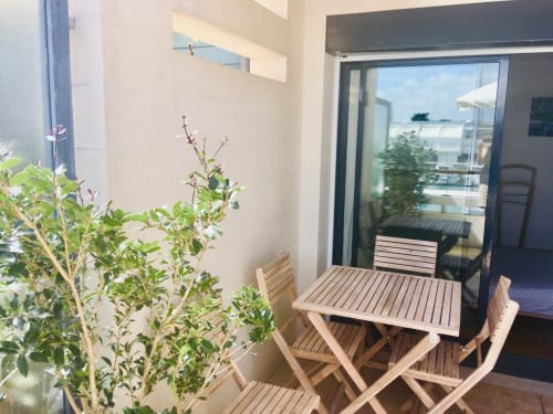 Terrasse privée de l'appartement Le Chalutier à La Rochelle avec mobilier de jardin en bois, plantes en pot et vue sur la rivière