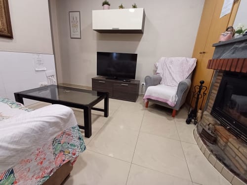 Modern living room in Algemesi apartment with sofa, TV, fireplace, and tile flooring