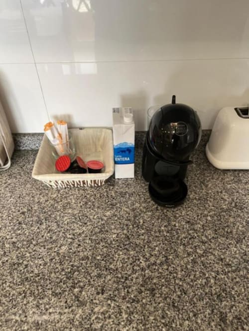Kitchen counter at Algemesi Home apartment with coffee maker, utensil holder, and cleaning supplies on granite countertop