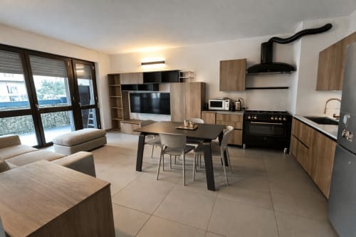 Modern open-plan apartment in Milano with kitchen, dining area, living room with TV, and balcony access