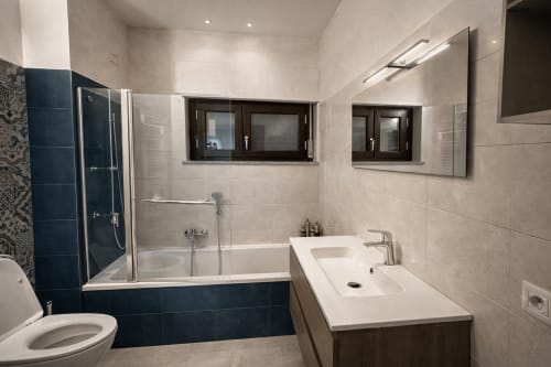 Modern bathroom in HBHALL Garden Apartment, Milano, featuring glass shower enclosure, vanity sink, and blue tile accents