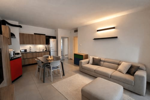 Modern open-plan apartment in Milano with kitchen, dining area, and living room with beige sofa