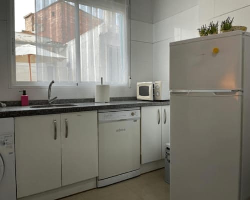 Modern kitchen in Algemesí Home apartment with white cabinets, black countertop, stainless steel appliances, and city view