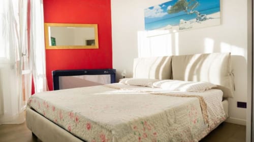 Bright bedroom at Versilia Panoramic Luxury hotel in Como, Italy, with cream upholstered bed, striped headboard, red accent