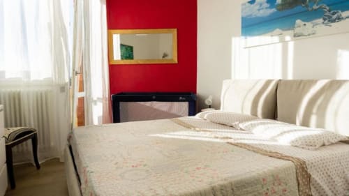 Bright bedroom in Versilia Panoramic Luxury apartment in Como with striped headboard, cream bedding, red accent wall, and