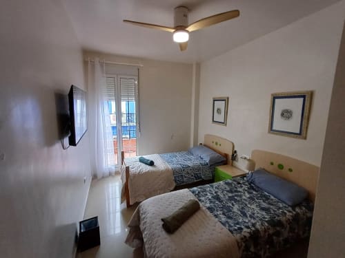 Twin bedroom at Algemesi Home with city views, ceiling fan, TV, and balcony access in Algemesí