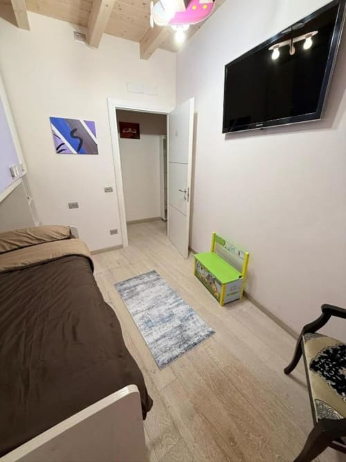 Modern Toscana apartment bedroom with TV, wooden ceiling, minimalist decor at Versilia Luxury