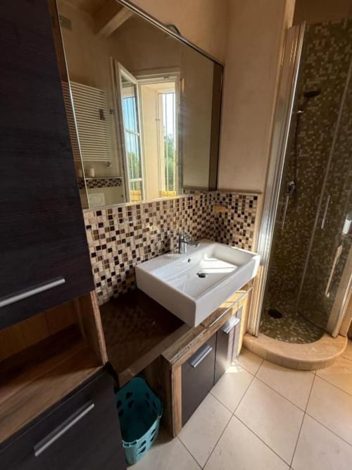Modern bathroom at Versilia Panoramic Luxury, Como. White sink, mosaic tile backsplash, mirror, and walk-in shower.