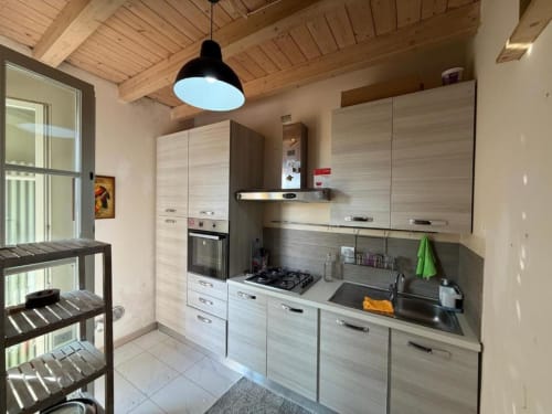 Modern kitchen in Il Tuo Rifugio apartment at Versilia Panoramic Luxury, Como Tuscany with light wood cabinets and black