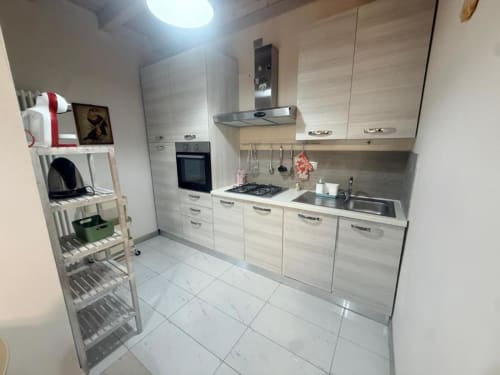Modern kitchen in Versilia Panoramic Luxury apartment with light wood cabinetry, stainless steel appliances, and white tile