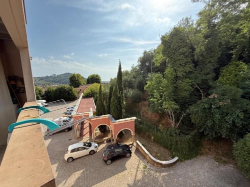 Luxury Tuscan apartment with scenic terrace overlooking hills, featuring playful car-themed decor and lush gardens at
