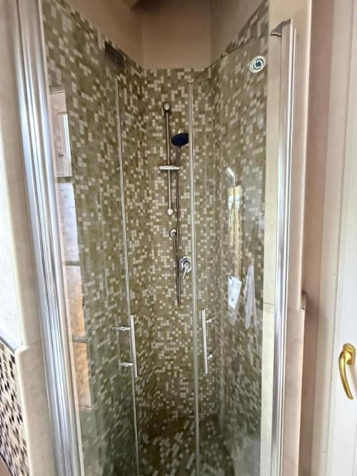 Modern glass shower enclosure with mosaic tile walls at Versilia Panoramic Luxury in Tuscany