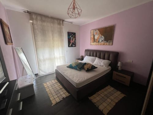 Sofy Penthouse bedroom at Versilia Panoramic Luxury, Como with pink walls, dark bed, and modern geometric pendant light