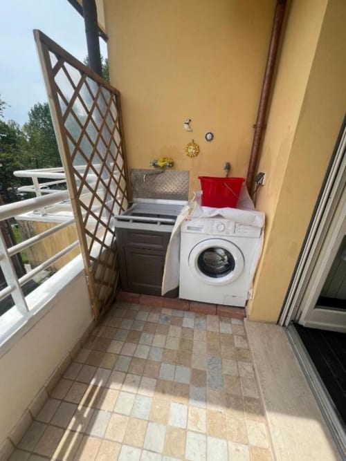 Balcony laundry area at Versilia Panoramic Luxury penthouse in Como with washing machine and yellow walls