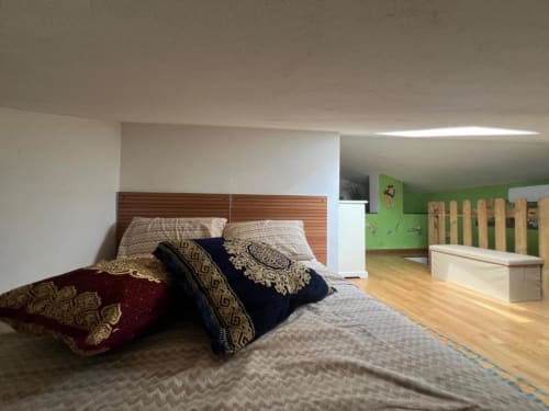 Sofy Penthouse bedroom with wooden headboard, decorative pillows, and green playroom area at Versilia Panoramic Luxury, Como
