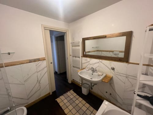 Modern bathroom in Sofy Penthouse at Versilia Panoramic Luxury hotel in Como, Italy with marble tiles and wooden accents