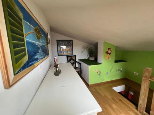 Bright loft-style room with green accent wall, artwork, and wooden flooring in Versilia Luxury penthouse