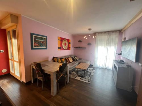 Sofy Penthouse living area at Versilia Panoramic Luxury, Como - pink walls, modern sofa, dining table, natural light from